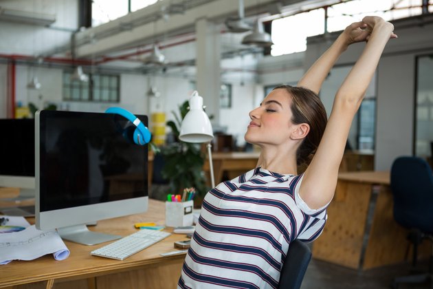 Female graphic designer sitting on chair and stretching her arms