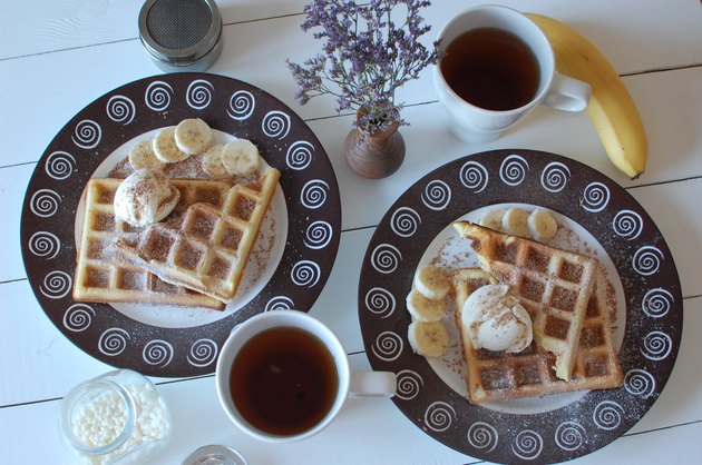 two white ceramic mugs beside plate of belgian waffles