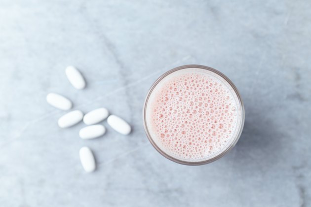 Glass of Protein Shake with milk and raspberries and BCAA amino acids in background. Sport nutrition. Stone background. Directly Above. Copy space.
