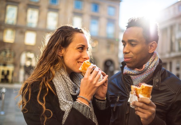 Young couple eating bread outdoors for carb diet