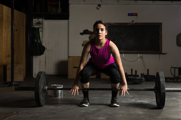 Young woman about to lift a barbell to perform deadlift variations