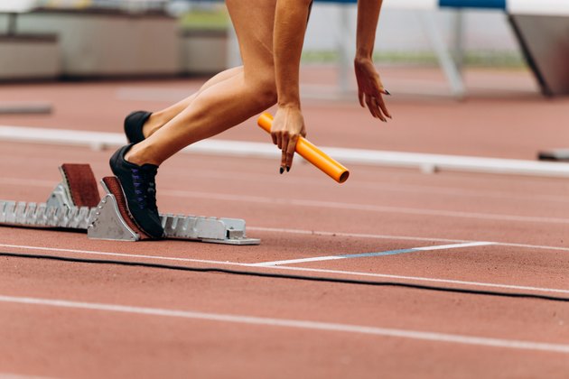 start female runner with baton in hand relay race running