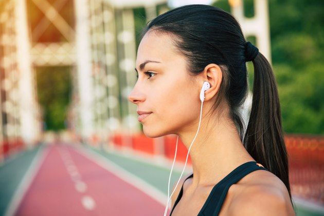 穿着运动服戴着耳机的女子在跑道上听着有氧运动的播放列表