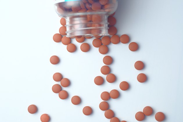 red pills spilling on white background, top view