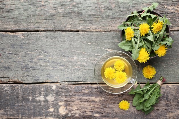 Yellow dandelions with cup of tea on gray wooden table
