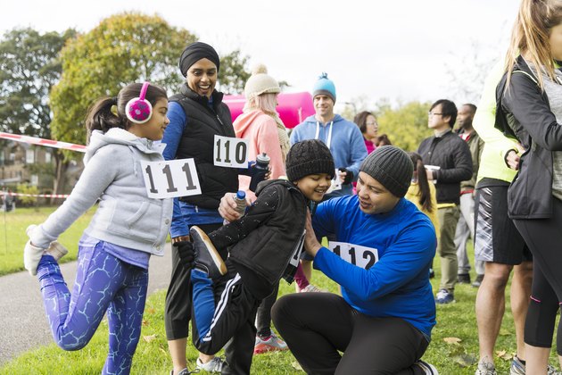 A family of runners preparing for a turkey trot, stretching in the park