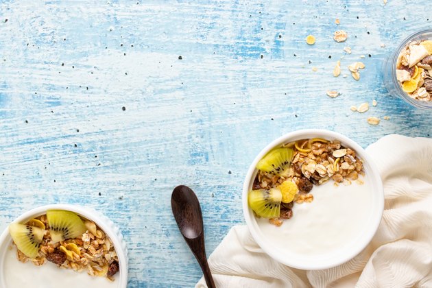 Top view of yogurt in bowl with granola,fresh kiwi on wooden table. Health food concept.