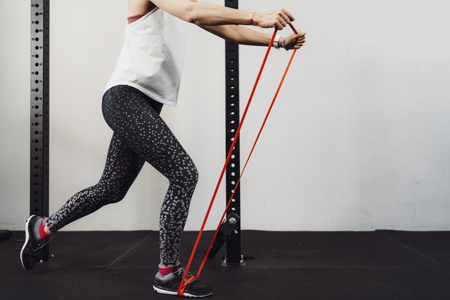 Unrecognizable woman in sports clothes working out with elastic band
