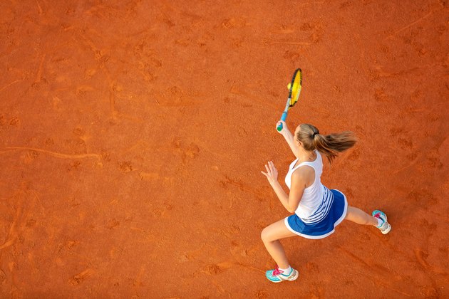 Aerial shot of a female tennis player on a court during match. Young woman playing tennis.High angle view.
