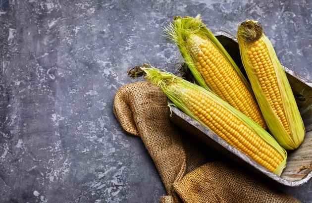 Corn in wooden basket on concrete surface