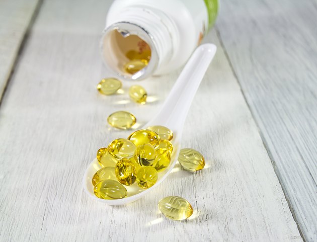 Primrose vitamin in whith spoon on wooden background