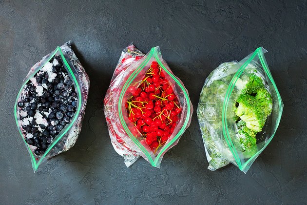 冰冻的浆果和蔬菜在袋子包装在黑色的混凝土背景-特写