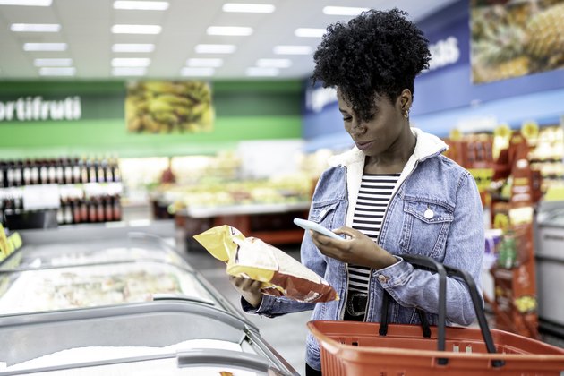 女人是在超市购物，并用智能手机扫描条形码“itemprop=