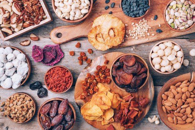 Mix of dried fruits and nuts -brazil nuts, cashew, pecan, almonds, macadamia, pine nuts, hazelnuts, pineapple, raisins, dates, dried apricots, goji, papaya, figs, mulberry on wooden background.Top view. Superfood, vegan, vegetarian concept