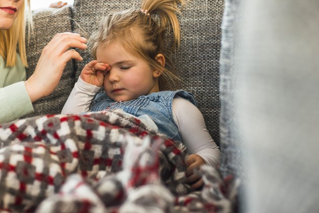 Exhausted girl on couch rubbing eyes