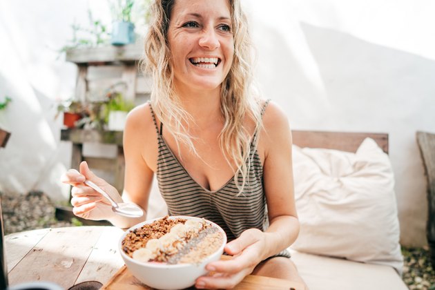 older woman smiling and eating a healthy breakfast bowl