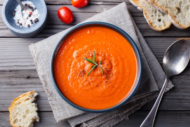 Tomato cold soup recipes in a black bowl on wooden background. Top view. Copy space