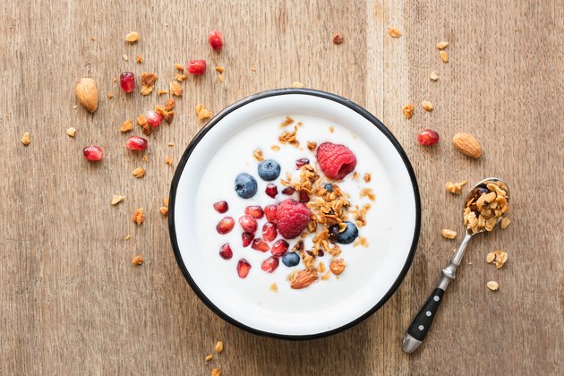 Greek yogurt with granola and berries on wooden table