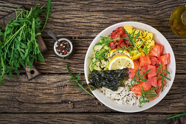 Hawaiian salmon fish poke bowl with rice, avocado, mango, tomato, sesame seeds and seaweeds. Buddha bowl. Diet food. Top view. Flat lay