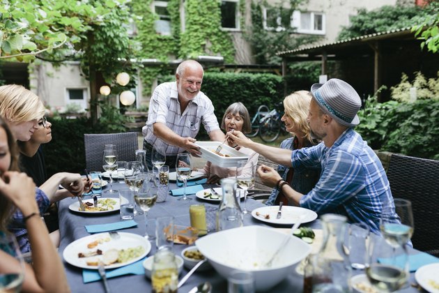 Family Sharing Food At BBQ In Courtyard Together