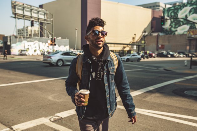 Portrait of stylish young man with coffee on the street