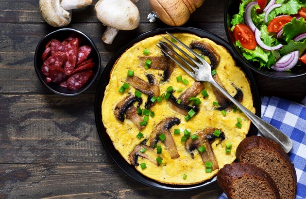 Frittata with mushrooms and cheese for breakfast with salad on a wooden background.