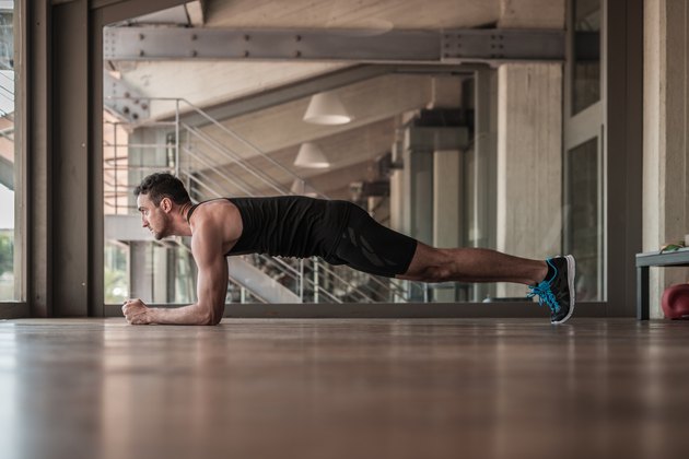 Mid adult man doing plank exercise with towel