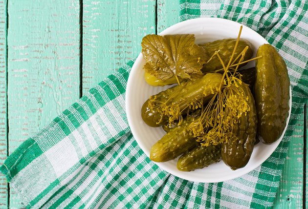 Pickled cucumbers on wooden background.