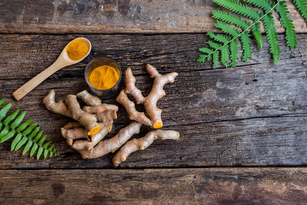 Fresh turmeric and powder curcumin on old wooden background, copy space