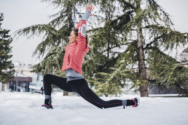 Woman doing yoga poses outside near a pine tree for stress relief during the holidays