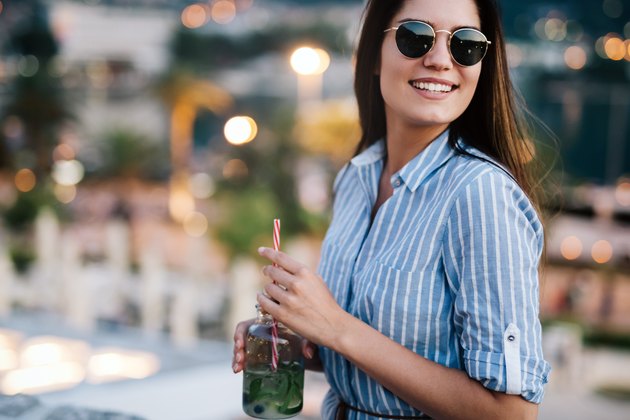Beautiful young happy woman smiling and drinking cocktail