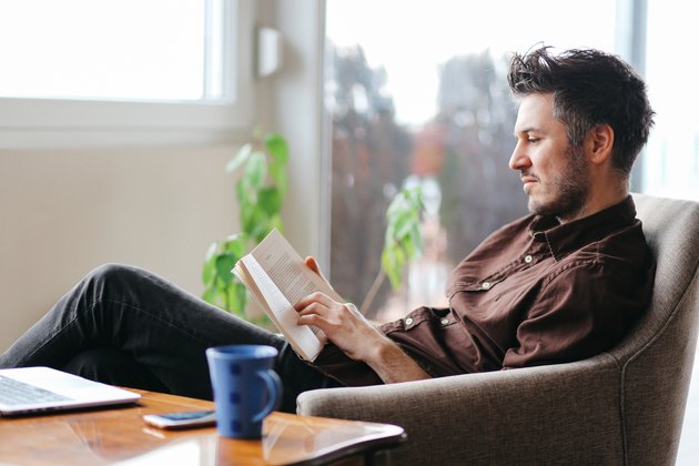 Young man reading a book at home