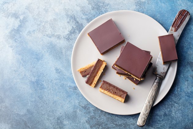 巧克力焦糖片，巧克力条，百万富翁用灰色盘子做的面包。蓝色背景。俯视图。
