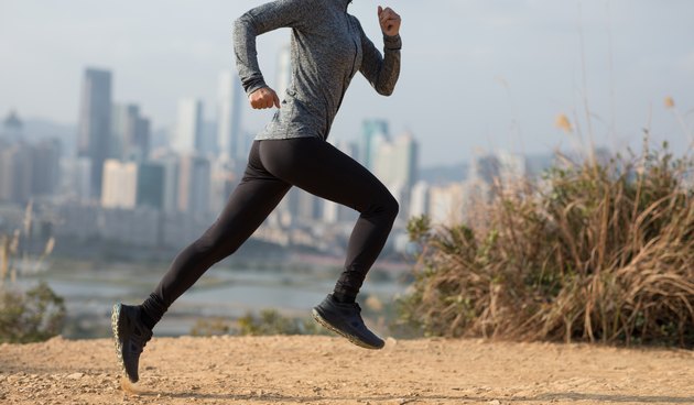 Female runner running on mountains next to modern city