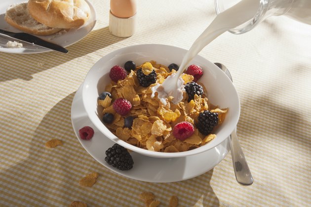 Milk being poured on a bowl of cornflakes with fruit