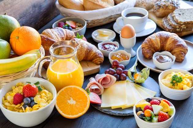A table set with a variety of breakfast foods, including cereal, croissants, scrambled eggs and fruit