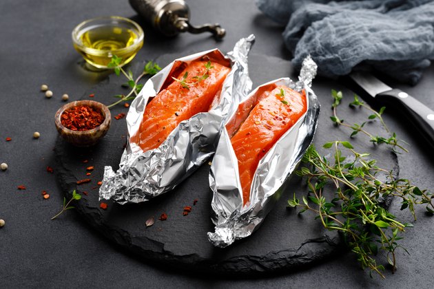 Raw salmon fish fillet in foil on black background