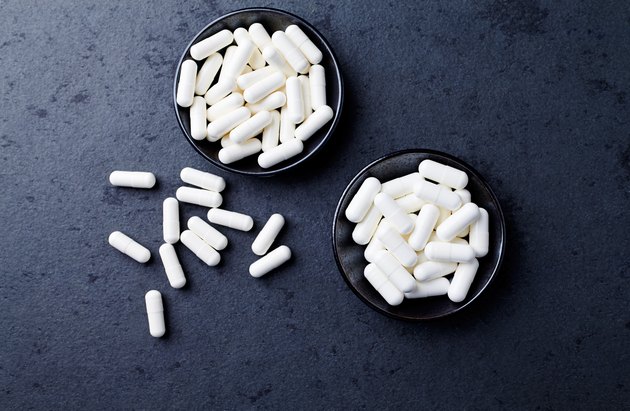 Arginine alpha-ketoglutarate (AAKG) and Creatine capsules. Bodybuilding food supplements on dark stone background. Directly Above. Copy space.