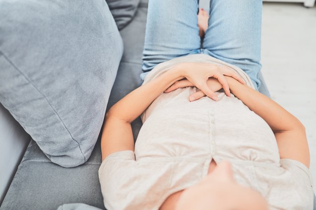 Woman with stomach issues / problems while lying on the couch.