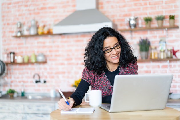 Mid adult woman working and using laptop at home