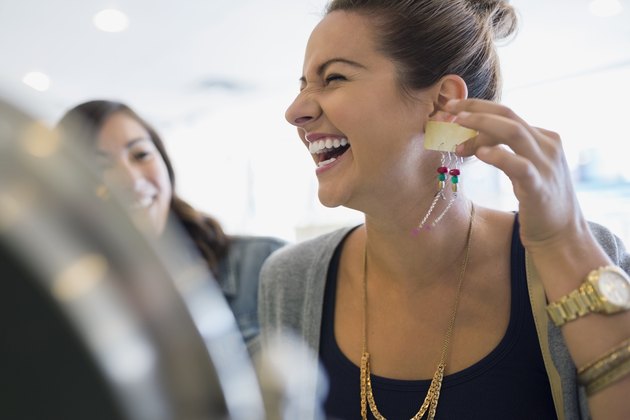 Laughing woman holding earrings in shop