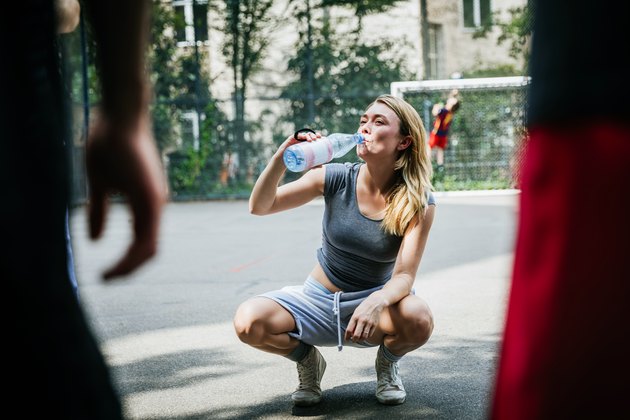Young Woman Taking Break From Basketball Game To Drink Water