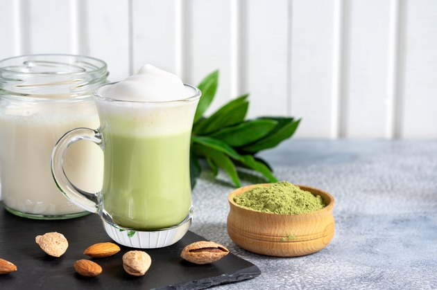 Matcha cappuccino with almond milk cup close-up background blurred.