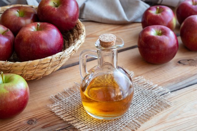 A bottle of apple cider vinegar with apples