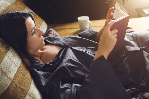 Woman relaxing in bed with her favorite book