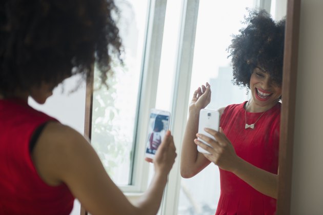 A woman taking a photo of herself in the mirror to track her weight-loss progress