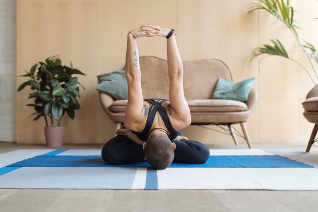 short haired woman practicing yoga lotus pose in home loft interior