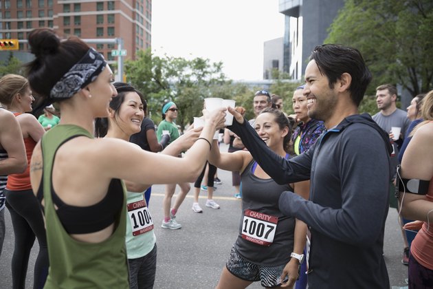 Four marathon runners toasting glasses on an urban street