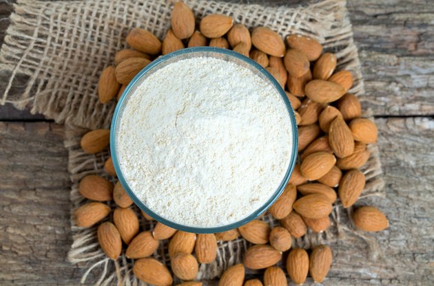 Almonds and almond flour on wooden surface