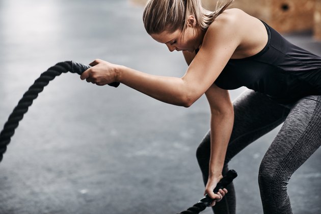Fit jeune femme balançant des cordes pendant l'entraînement de gym